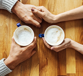 Couple discussing financial goals over coffee with Guardian Credit Union support