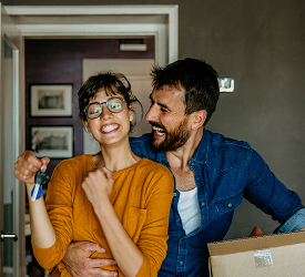Happy couple holding house keys and moving in, representing Guardian Credit Union’s government-backed home loan options