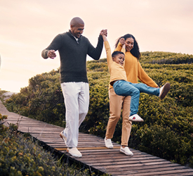 Smiling family walks outdoors, representing Guardian CU’s life insurance protection.