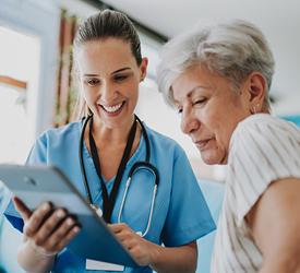 Smiling nurse reviewing information with older patient, representing Guardian CU’s health insurance support and coverage options