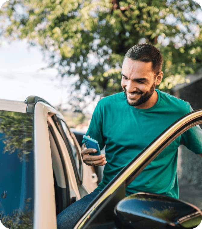 Smiling man getting out of car while using mobile banking through Guardian Credit Union auto loan services