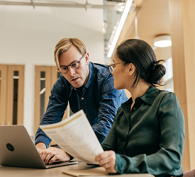Two professionals review documents, representing Guardian CU’s employee benefits options.