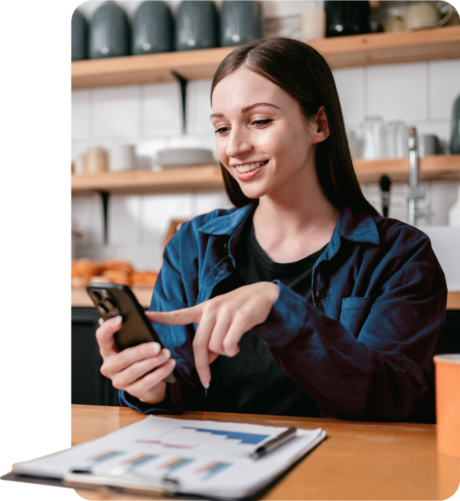 A woman uses her cellphone in the kitchen to review her direct deposit in mobile banking, enabling her to plan her finances.