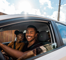 Smiling man driving with friends, representing the freedom and ease of Guardian Credit Union auto loan options