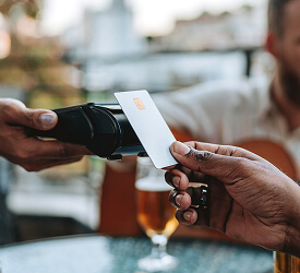 Member making a contactless payment at an outdoor café, showing the ease of Guardian debit and credit cards