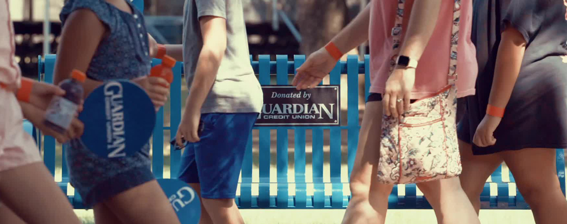 Guardian Credit Union bench surrounded by people passing by — representing our commitment to serve the community whenever it’s needed.