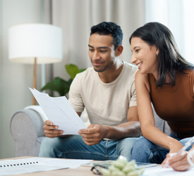 Smiling couple reviews documents at home with Guardian Financial Planning for retirement readiness
