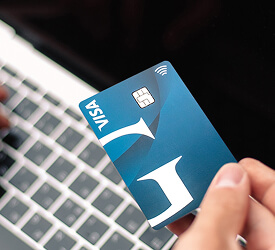 Person holding Guardian Credit Union Visa credit card near a laptop, representing secure credit-building tools