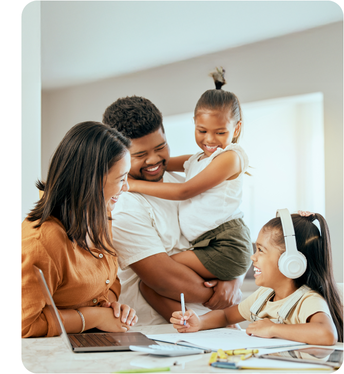 A smiling family sitting at home, surrounding themselves with a laptop and a notebook, suggesting that financial learning is fun and necessary for the members of the family.