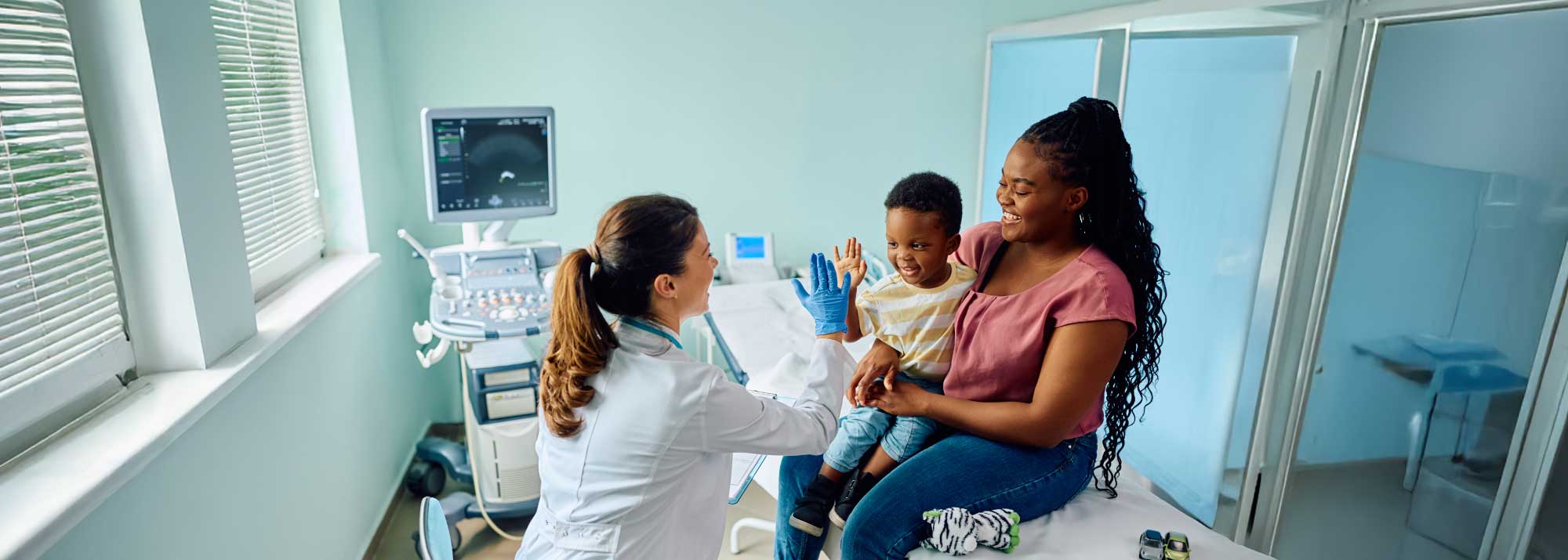 young child with his mother high-fiving the doctor while using the benefits from Guardian Credit Union Affortable Health Insurance