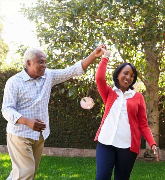 Smiling retired couple dancing in their backyard, relieved to be free from financial worries.