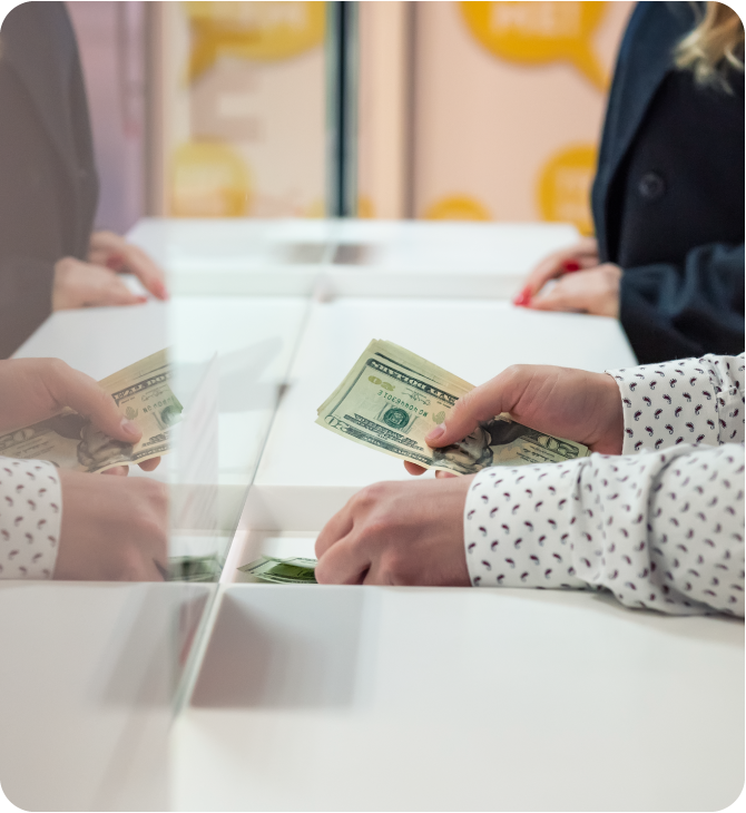 Person exchanging cash at a teller counter, illustrating credit builder strategies and financial responsibility