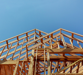 Framing of a new home under blue sky, representing construction loan options available through Guardian CU’s Home Loans