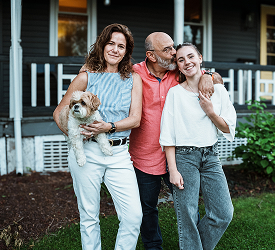 Smiling family with dog in front of home, showcasing Guardian CU’s home insurance.